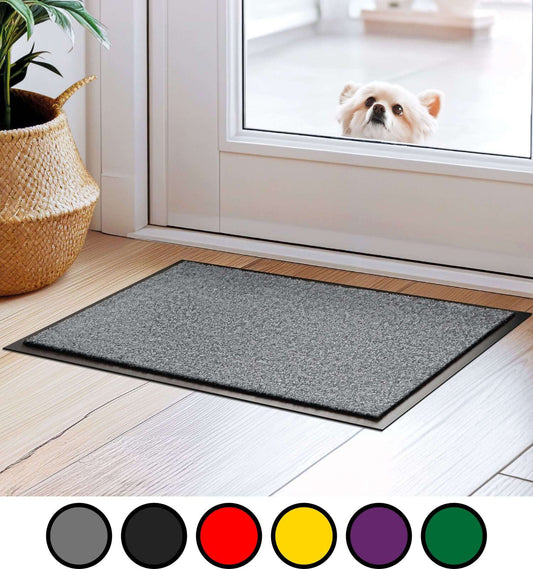 Schmutzfangmatte liegt im Eingangsbereich auf braunem Parkettboden. Hinter der Glastür schaut ein Hund ins Haus rein. 