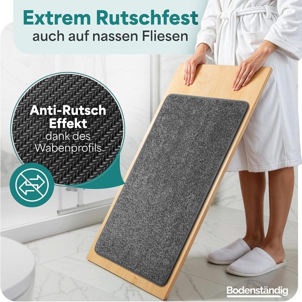 Rutschfeste graue Badematte auf schraeger Holzplatte demonstriert starken Halt durch Wabenprofil, ideal fuer nasse Fliesen im Badezimmer