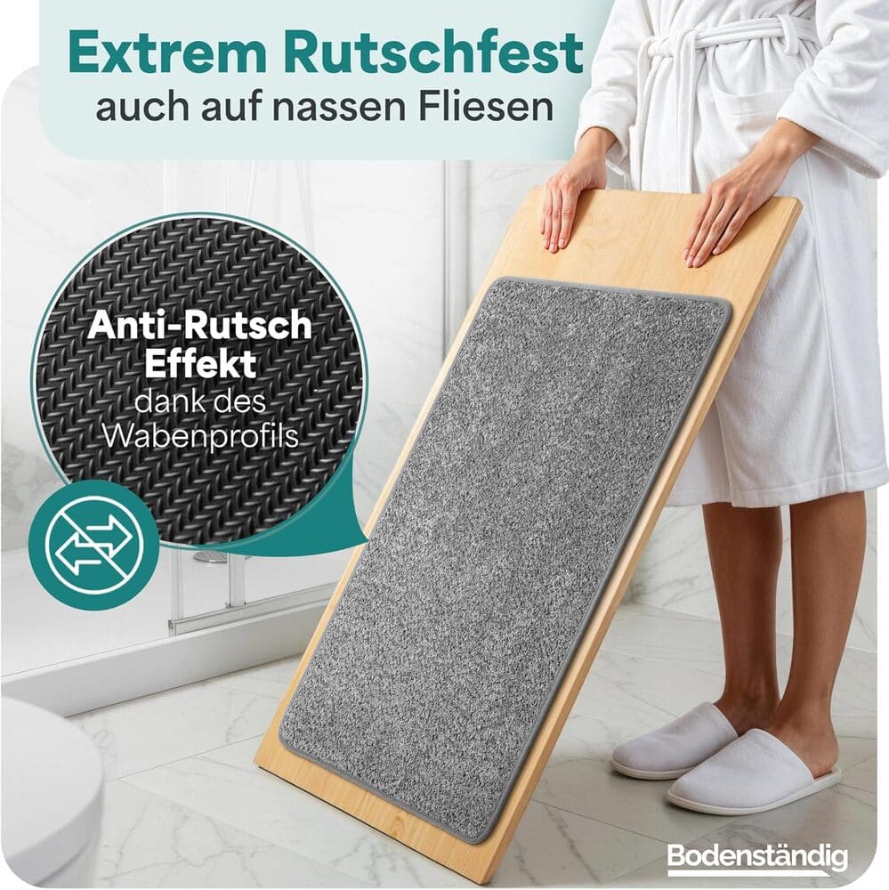 Rutschfeste graue Badematte auf schraeger Holzplatte demonstriert starken Halt durch Wabenprofil, ideal fuer nasse Fliesen im Badezimmer