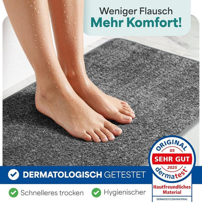 Nasse Fuessse auf rutschfester grauer Badematte, dermatologisch getestet, schnelles Trocknen und hygienisches Material fuer das Badezimmer