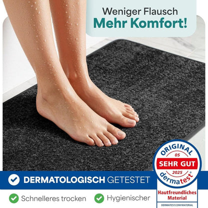 Nasse Fuessse auf rutschfester grauer Badematte, dermatologisch getestet, schnelles Trocknen und hygienisches Material fuer das Badezimmer