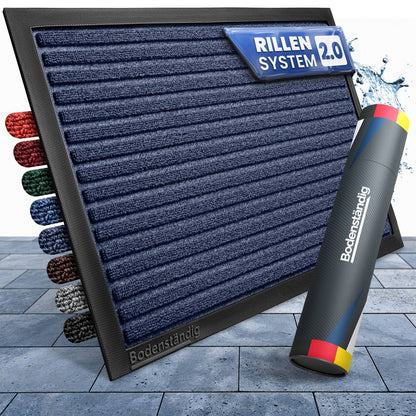 Dunkelblaue gerillte Fußmatte mit Rillensystem 2.0, Farbmustern am Rand und Bodenständig-Verpackungsrolle auf Steinplatten
