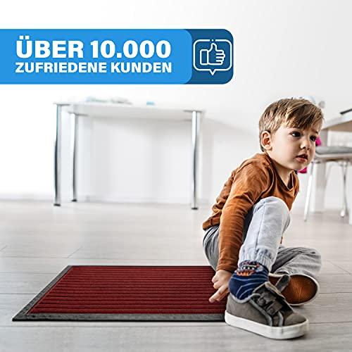 Kind sitzt auf einer dunkelroten Fussmatte, die rutschfest ist und von vielen zufriedenen Kunden genutzt wird.