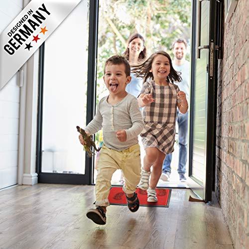 Kinder rennen in den Flur und laufen ueber eine rote Fussmatte, waehrend Erwachsene an der offenen Haustuer stehen.