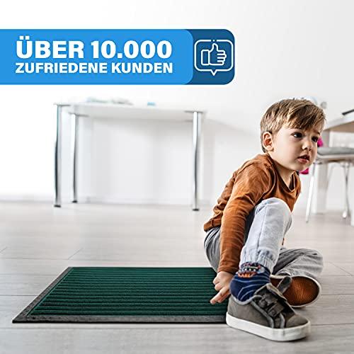 Kind sitzt auf einer gruenen Fussmatte im hellen Raum, die rutschfest ist und von vielen zufriedenen Kunden genutzt wird.