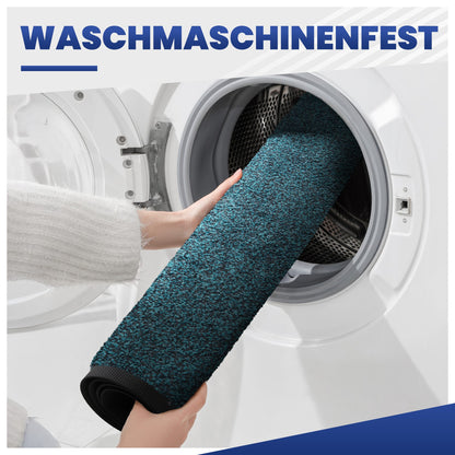Hand schiebt eine blaue, aufgerollte Fußmatte in eine Waschmaschine, Text: Waschmaschinenfest