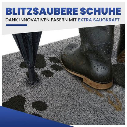 Graue Schmutzfangmatte mit Pfotenmotiv, darauf ein nasser Gummistiefel und Regenschirm; Text: Blitzsaubere Schuhe