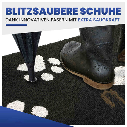 Schwarze Fußmatte mit weißen Pfoten, darauf nasser Gummistiefel und Regenschirm, Text Blitzsaubere Schuhe