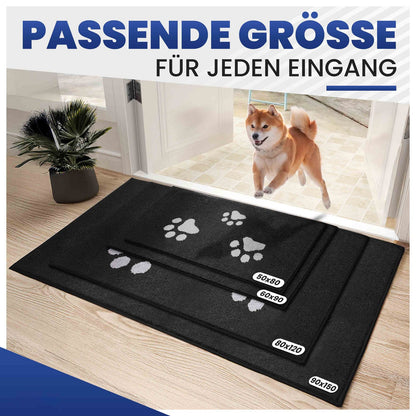 Vier schwarze Fußmatten mit weißen Hundepfoten in vier Größen vor einer Tür, Shiba Inu läuft darauf zu