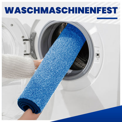Blaue Fußmatte, zusammengerollt in eine Waschmaschine geschoben, Text „Waschmaschinenfest“