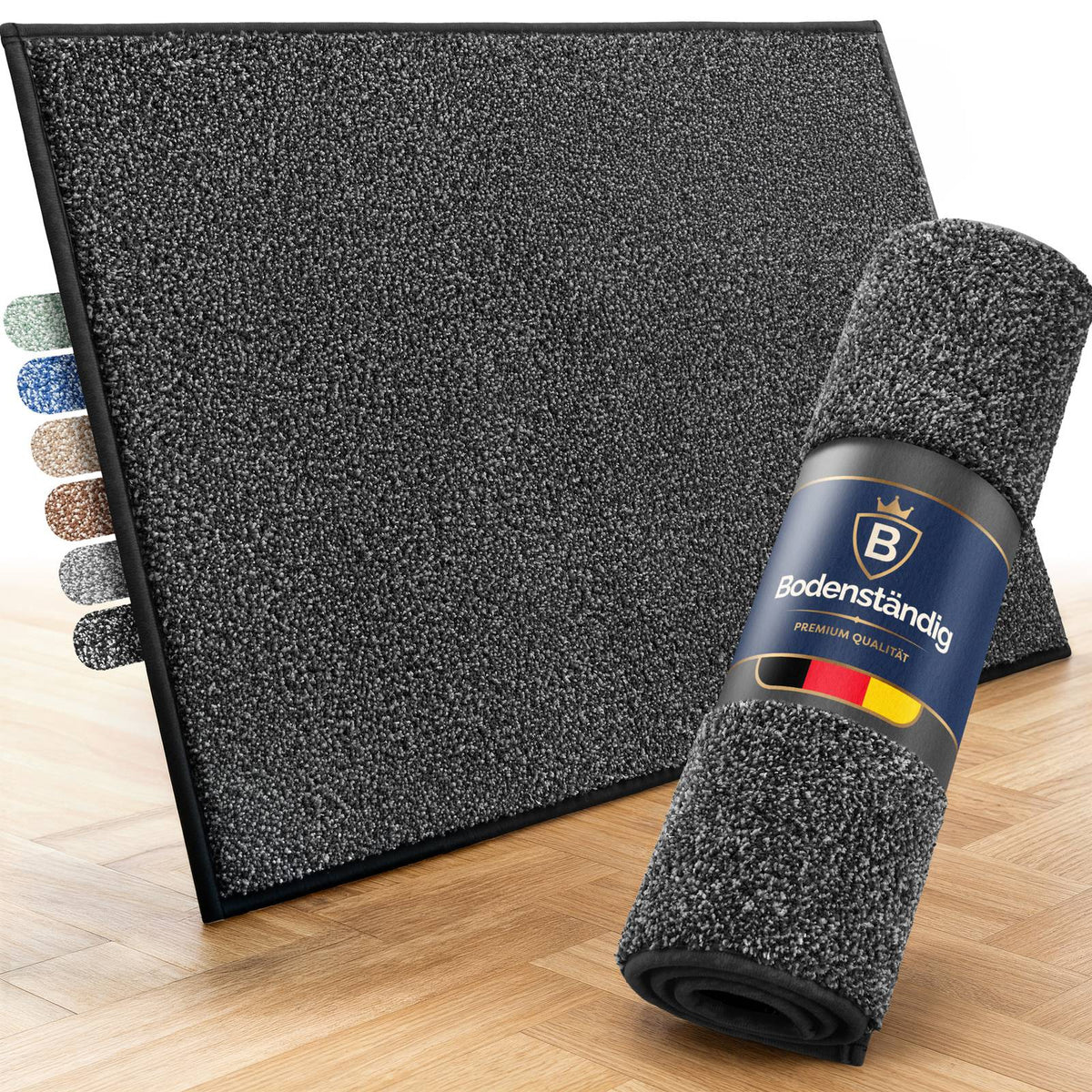 Graue Fußmatte von Bodenständig, aufgestellt auf Parkett, davor eine aufgerollte Matte mit Banderole und Farbmustern links