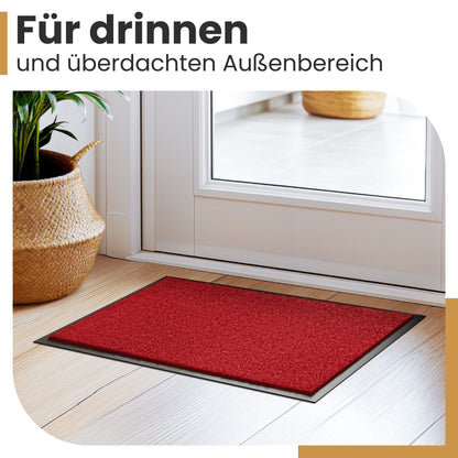 Rote Fußmatte vor einer weißen Haustür neben einem Korb mit Pflanze, Text „Für drinnen und überdachten Außenbereich“