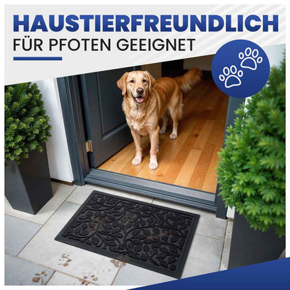 schwarze fussmatte mit blattmuster fuer innen am hauseingang geeignet fuer haustiere hund steht auf holzboden und pfotenabdruecke sind sichtbar