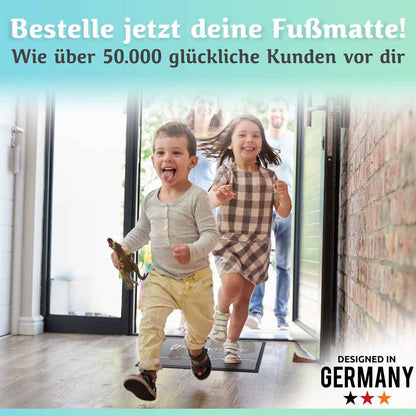 zwei kinder laufen lachend ins haus auf eine graue willkommen fussmatte ideal fuer eingangsbereiche designed in germany