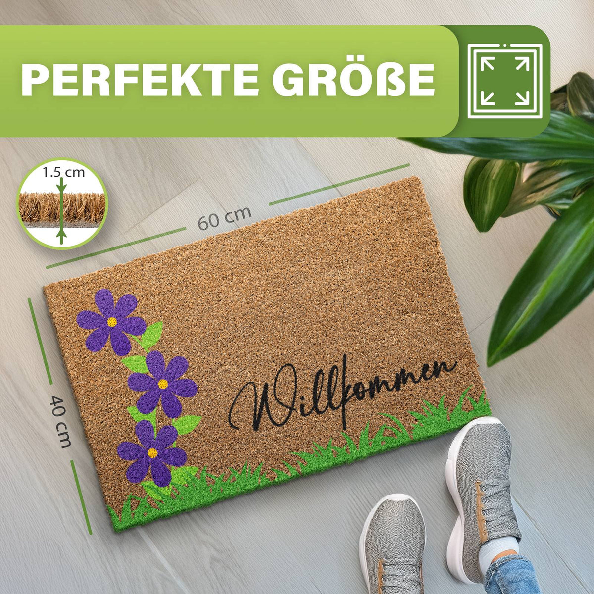 Kokosmatte „Willkommen“ mit lila Blumen und Gras, Maße 40 x 60 cm und 1,5 cm dick, daneben Schuhe und Pflanze