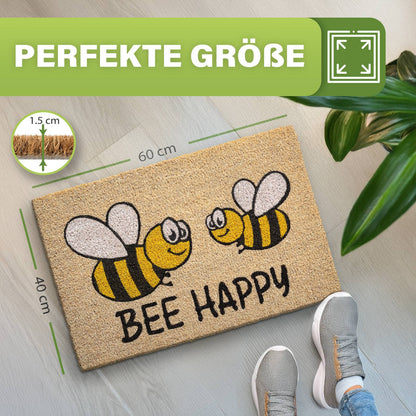 Kokosmatte „Bee Happy“ mit zwei Bienen, Maße 40 x 60 cm und 1,5 cm dick, daneben Schuhe und Zimmerpflanze