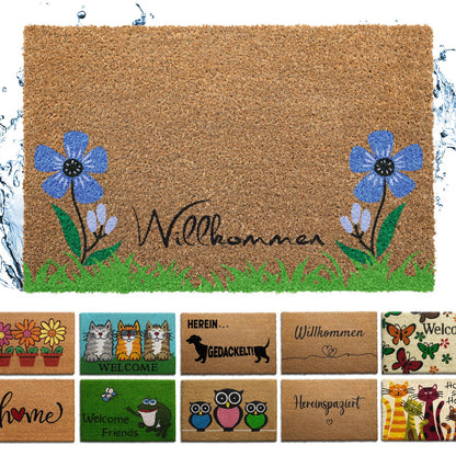 Naturfarbene Kokos-Fußmatte mit Schriftzug „Willkommen“, blauen Blumen und Gras, darunter weitere Mattenmotive