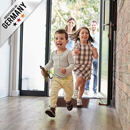 Kinder rennen in den Flur und laufen ueber eine braun Fussmatte, waehrend Erwachsene an der offenen Haustuer stehen.