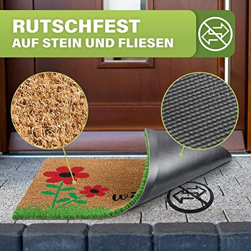 Kokos-Fußmatte "Willkommen" mit Blumenmotiv, die hochgeklappt wird, um die rutschfeste Gummi-Unterseite zu zeigen. Sicher auf Stein und Fliesen.