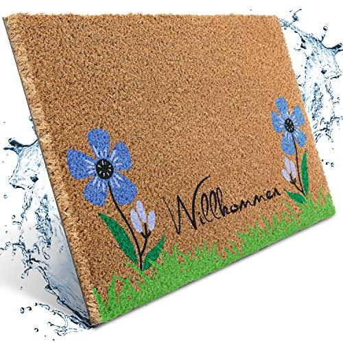 Natürliche Kokos-Fußmatte mit dem Schriftzug "Willkommen" und einem Motiv aus hellblauen Blumen und grünem Gras.